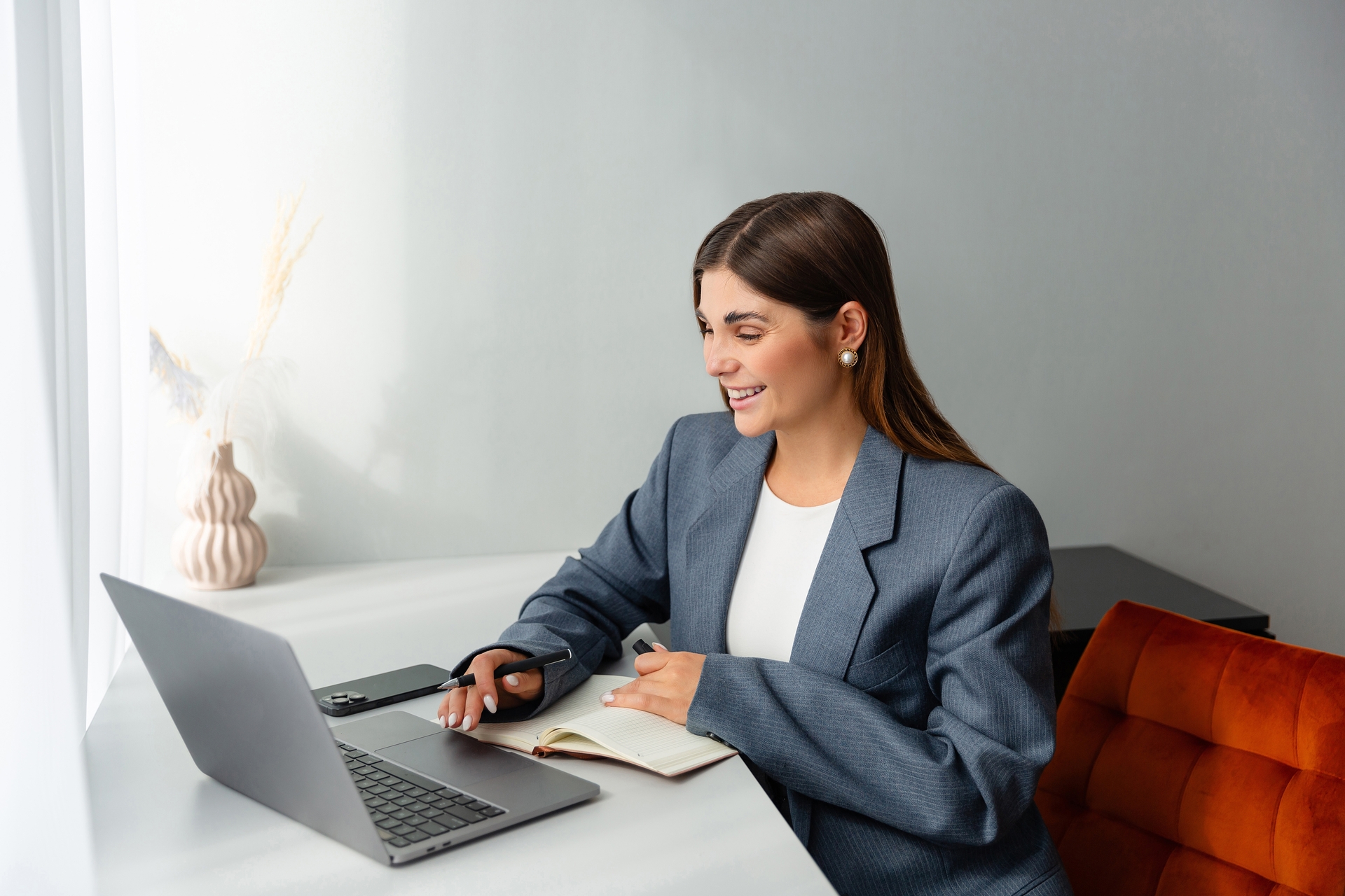 woman,in,a,blazer,working,at,her,desk,,holding,a